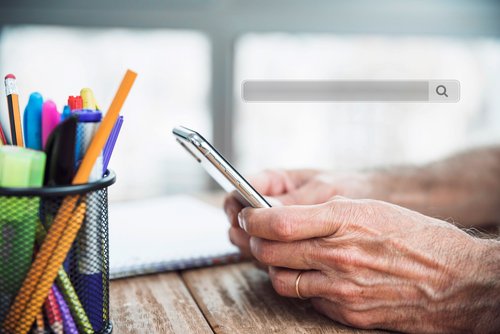 Hände eines älteren Menschen, der ein Mobiltelefon hält