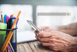 Hände eines älteren Menschen, der ein Mobiltelefon hält